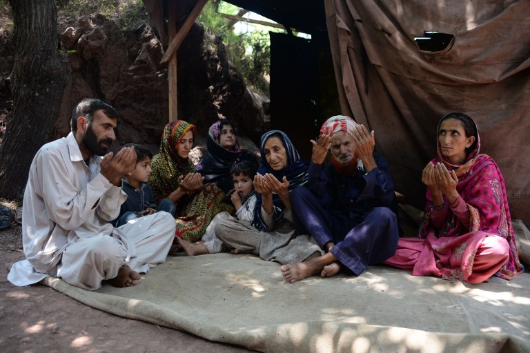 Makhni Begum (3R) and Shah Zula (2R), the parents of Pakistani Kashmiri convicted killer Shafqat Hussain, pray as they sit with relatives in Muzaffarabad, the capital of Pakistani-administered Kashmir on June 9, 2015. Relatives of a Pakistani death row prisoner said that they "felt a wave of life" when his execution was halted to examine claims he was a juvenile when the crime was committed.  AFP PHOTO/ Sajjad QAYYUM