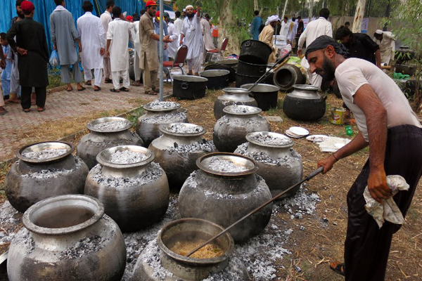 Pakistani men prepare food for internally displaced civilians fleeing a military operation against Taliban militants in North Waziristan, at the end of the fasting month of Ramadan in Bannu on July 28, 2014. Muslims around the world are celebrating the Eid al-Fitr holiday, which marks the end of the fasting month of Ramadan. AFP PHOTO/ KARIM ULLAH